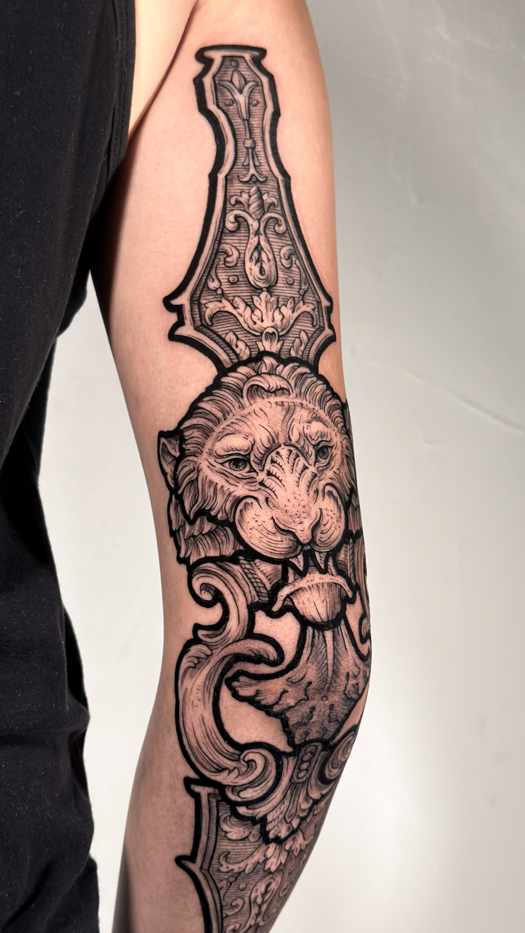 Engraving-style lion and ornate dagger sleeve tattoo